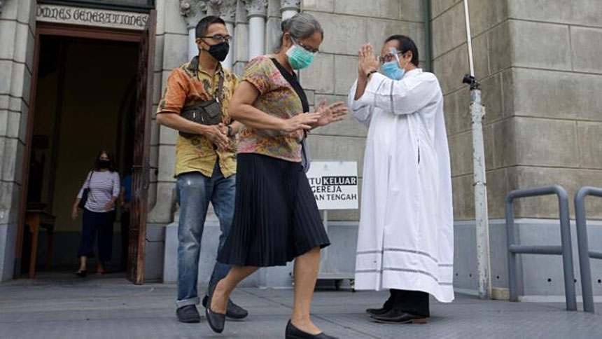CNS: Priest wearing a protective face mask greets parishioners