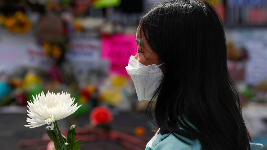 A girl in Atlanta holds a flower March 21, 2021, during a vigil at a makeshift memorial outside the Gold Spa following the deadly shootings March 16 at three day spas in metro Atlanta. (CNS photo/Shannon Stapleton, Reuters)