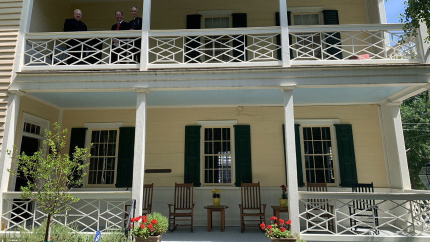 Father Thomas Tully, pastor of New Bern’s St. Paul Church, John L. Barnes, owner of the Coor-Gaston House, and Bishop Luis Rafael Zarama stand on a porch of home, where Bishop John England celebrated Mass May 24, 1821. With that Mass, the Catholic community of New Bern had its official beginning.   