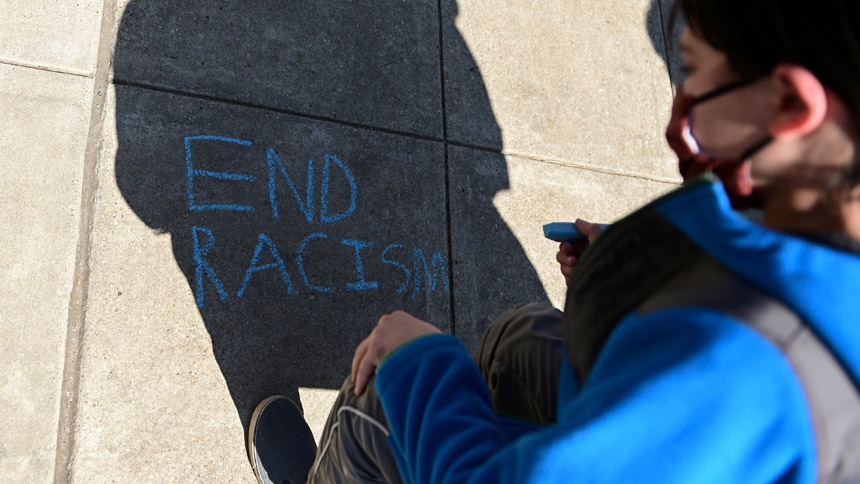 A child in Washington writes in chalk, "End racism," as people rally to protest recent violence against people of Asian descent March 21, 2021. (CNS photo/Erin Scott, Reuters)
