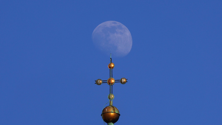  The rising moon is seen above a cross on top of a church in downtown Lviv, Ukraine, March 14, 2022. (CNS photo/Kai Pfaffenbach, Reuters)