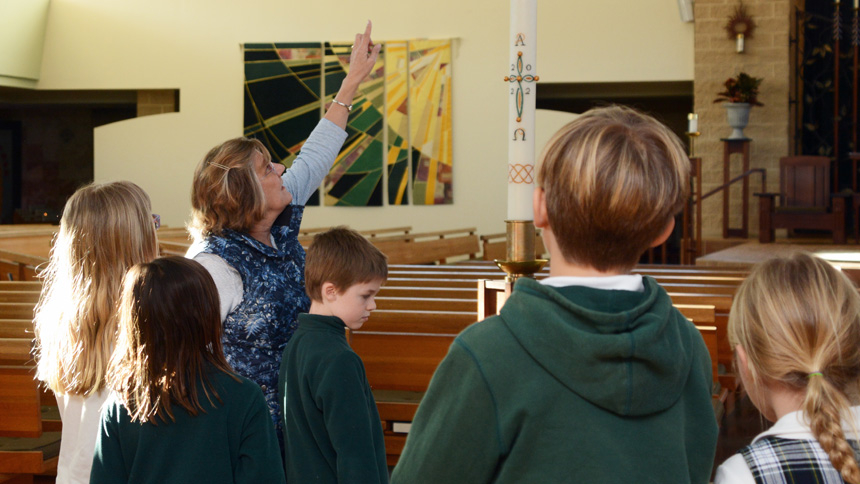 Patti Wagner shows the children the Easter candle in the St. Thomas More Church.