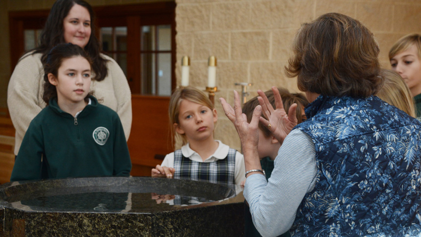 Patti Wagner and Julie Hall show the students the baptismal font in the St. Thomas More Church.
