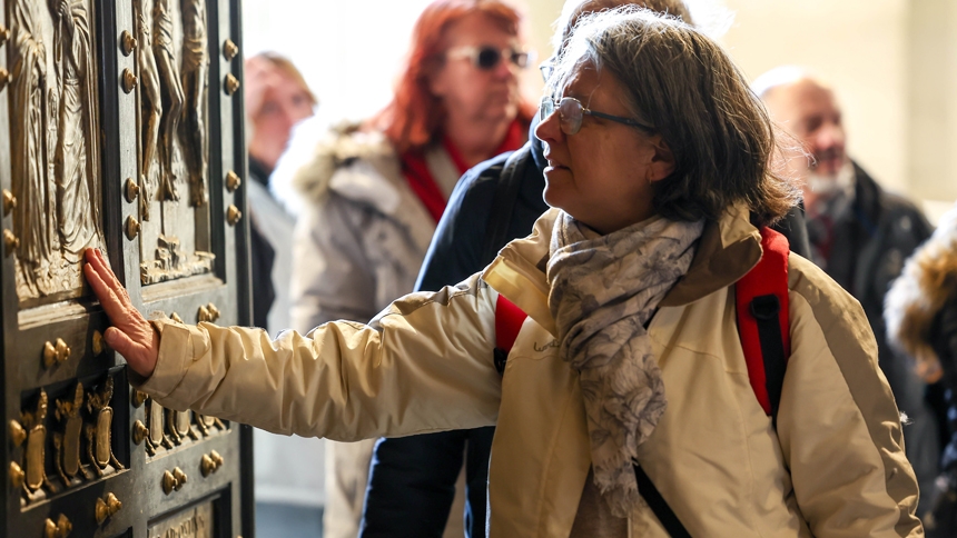 A visitor touches the Holy Door of St. Peter’s Basilica on Christmas Day, Dec. 25, 2024, after it was opened by Pope Francis during Christmas Mass the night prior to mark the start of the Holy Year 2025. (CNS photo/Lola Gomez)