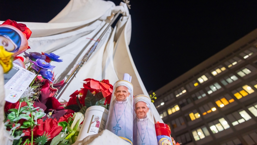 Votive candles and flowers are seen at the base of a statue of St. John Paul II outside Rome's Gemelli hospital Feb. 21, 2025, where Pope Francis is being treated for double pneumonia. (CNS photo/Pablo Esparza)