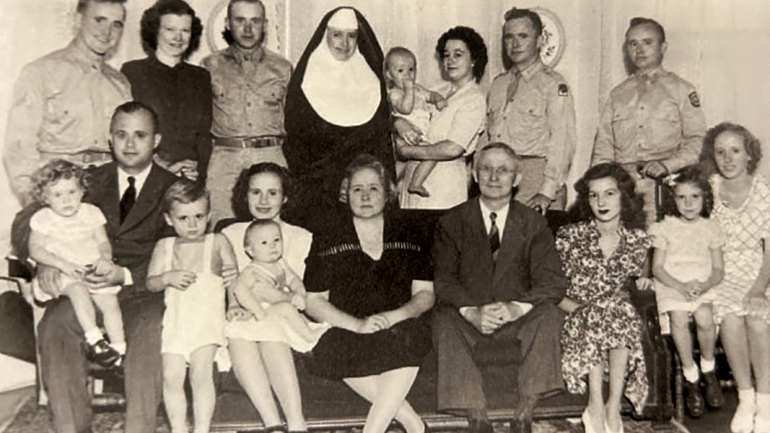 An infant Charlie is held by his mother in the back row of this family picture.
