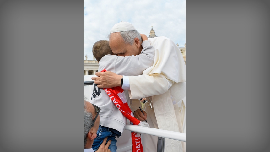 Pope Leo XIV gets a hug as he rides in the popemobile before his weekly general audience in St. Peter's Square at the Vatican Oct. 1, 2025. (CNS photo/Vatican Media)