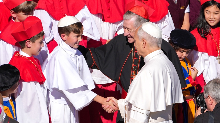 Pope Leo XIV greets fourth grader Augie Wilk, who was elected "Pope Augustine" in a mock conclave at Our Lady of Mount Carmel Academy in Chicago, during the pope’s weekly general audience in St. Peter's Square at the Vatican Oct. 8, 2025. Cardinal Blase J. Cupich of Chicago looks on. The students’ reenactment May 6 of a papal election went viral days before Pope Leo’s own election May 8. (CNS photo/Lola Gomez)