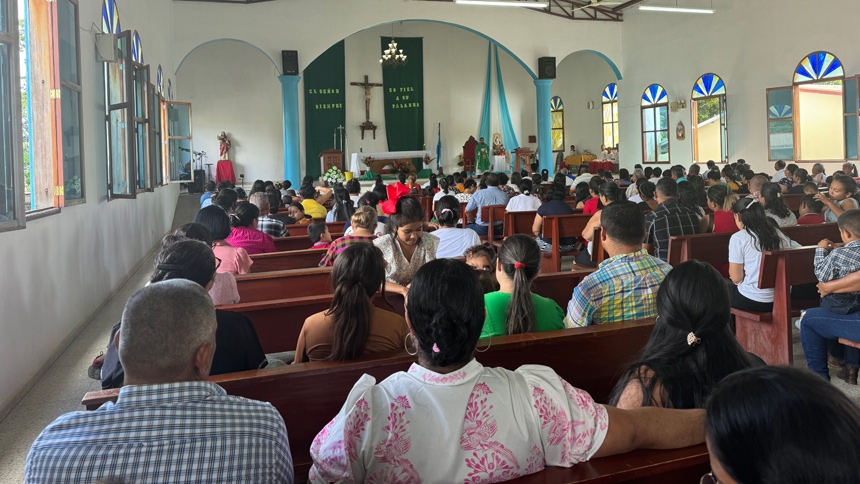 People celebrate Mass in one of the community churches St. Michael Parish helped to build. Banners by the crucifix translate to “The Lord is faithful to his word.”