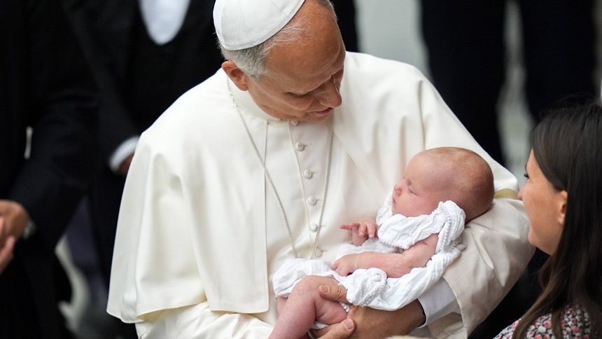 Pope Leo XIV holds a baby as he greets people in the Paul VI Audience Hall at the conclusion of his weekly general audience at the Vatican Aug. 20, 2025. (CNS photo/Lola Gomez)
