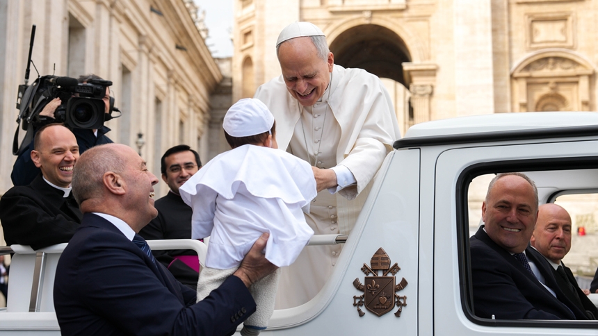 Pope Leo XIV smiles as he greets a child dressed as the pope from the popemobile while riding around St. Peter’s Square at the Vatican before his weekly general audience March 11, 2026. (CNS photo/Lola Gomez)