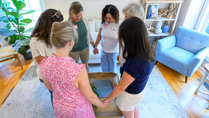 Members of the Women at the Well, a group at St. Francis of Assisi Parish, pray together before dinner July 29.