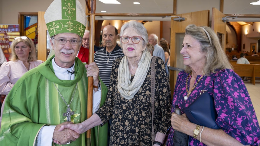 Bishop Luis, Trudy McNeil Young and her daughter Katherine Hufham stand with the bishop after Mass. Young’s father, Gus McNeil, donated part of the land that the original church was built on in 1941. 