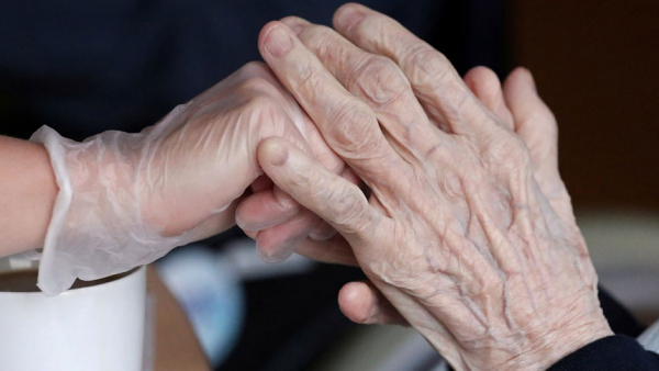  An employee holds the hand of a person at an elderly residence in Brussels April 14, 2020, during the COVID-19 pandemic. (CNS photo/Yves Herman, Reuters)
