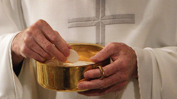 A priest prepares to distribute Communion during Mass in Washington. (CNS photo/Bob Roller)