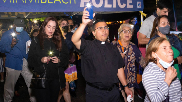 Father Jose Arroyo of the Diocese of South Bend-Fort Wayne, Ind., joined St. Joseph Parish in Miami Beach, Fla., and the parish youth ministry for a eucharistic prayer and candlelight vigil for those who have died and who are still missing June 26, 2021. The evening included a walkthrough of the neighborhood close to the site of the partially collapsed condo in Surfside, Fla. (CNS photo/Tom Tracy, Florida Catholic)