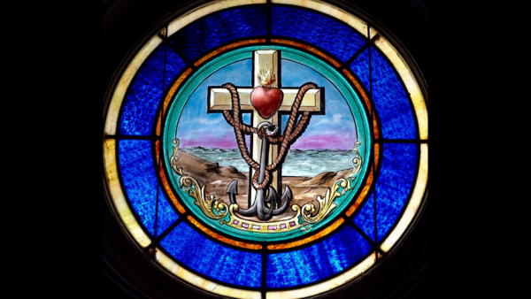 A stained-glass window at Holy Cross Catholic Church in East Bernard, Texas, depicts a symbol for Catholic seafarers. In a message for Sea Sunday July 11, the Vatican is calling for much greater protection for seafarers, who are responsible for handling 90% of the goods traded around the world. (CNS photo/Janet Jones, The Catholic Lighthouse)