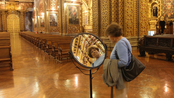 A visitor uses a mirror to take a closer look at the ornate architectural details of Quito's Iglesia de la Compania July 3, 2015. (CNS/Barbara Fraser)
