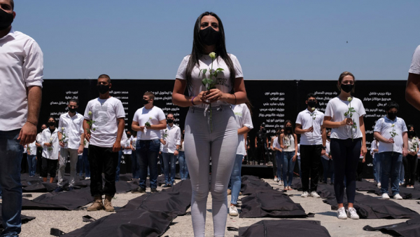 Students affiliated with the Lebanese Forces hold white roses and stand next to body bags in Beirut Aug. 4, 2021, in memory of victims of the 2020 Beirut port explosion. During his general audience Aug. 4, Pope Francis urged the international community to help Lebanon with concrete action so it may rise again as sign of peace and fraternity for the Middle East. (CNS photo/Emilie Madi, Reuters)