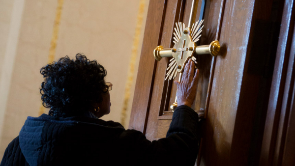 A woman touches a gold cross on the Holy Door before Mass at the Basilica of the National Shrine of the Immaculate Conception in Washington in this Dec. 8, 2015, file photo. Pope Francis has approved the theme "Pilgrims of Hope" to be the motto for the Holy Year 2025. (CNS photo/Jaclyn Lippelmann, Catholic Standard)