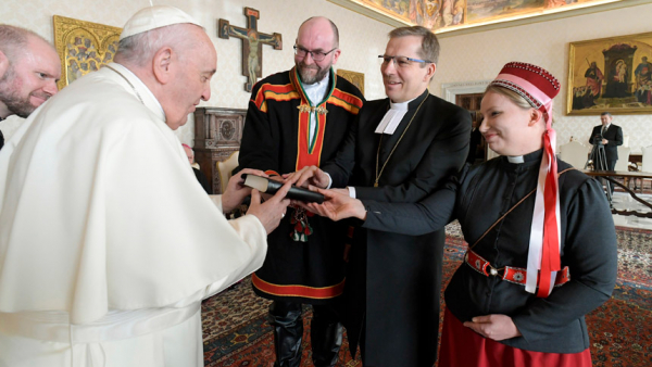 Pope Francis accepts a gift during an audience with an ecumenical delegation from Finland at the Vatican Jan. 17, 2022. Presenting the gift were Lutheran Bishop Jukka Keskitalo of Oulu, flanked by two Lutheran pastors, the Rev. Tuomo Huusko and the Rev. Mari Valjakka. The two pastors, who are wearing traditional Sámi dress, minister to the Indigenous community. (CNS photo/Vatican Media)