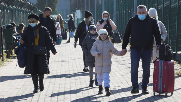 A family carrying their belongings walks at the border crossing between Poland and Ukraine in Medyka, Poland, Feb. 24, 2022, after Russian President Vladimir Putin authorized a military operation in Ukraine. (CNS photo/Kacper Pempel, Reuters)