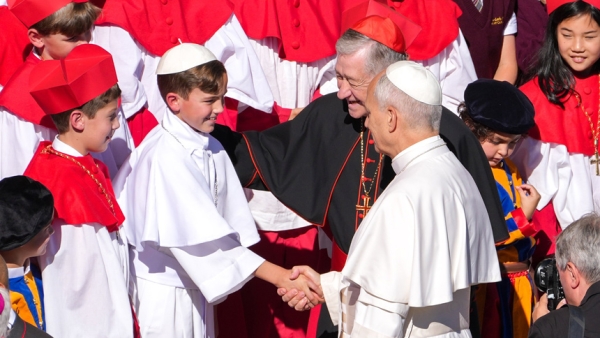 Pope Leo XIV greets fourth grader Augie Wilk, who was elected "Pope Augustine" in a mock conclave at Our Lady of Mount Carmel Academy in Chicago, during the pope’s weekly general audience in St. Peter's Square at the Vatican Oct. 8, 2025. Cardinal Blase J. Cupich of Chicago looks on. The students’ reenactment May 6 of a papal election went viral days before Pope Leo’s own election May 8. (CNS photo/Lola Gomez)